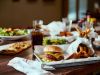 Table with plates of burgers and appetizers.