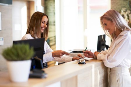 Picture of receptionist and businesswoman at hotel front desk, reviewing her stay