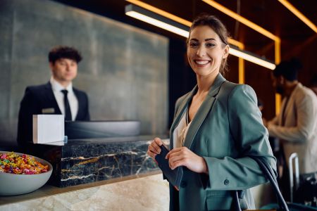 Happy entrepreneur arriving at the hotel during her business travel and looking at camera, leaving a good review