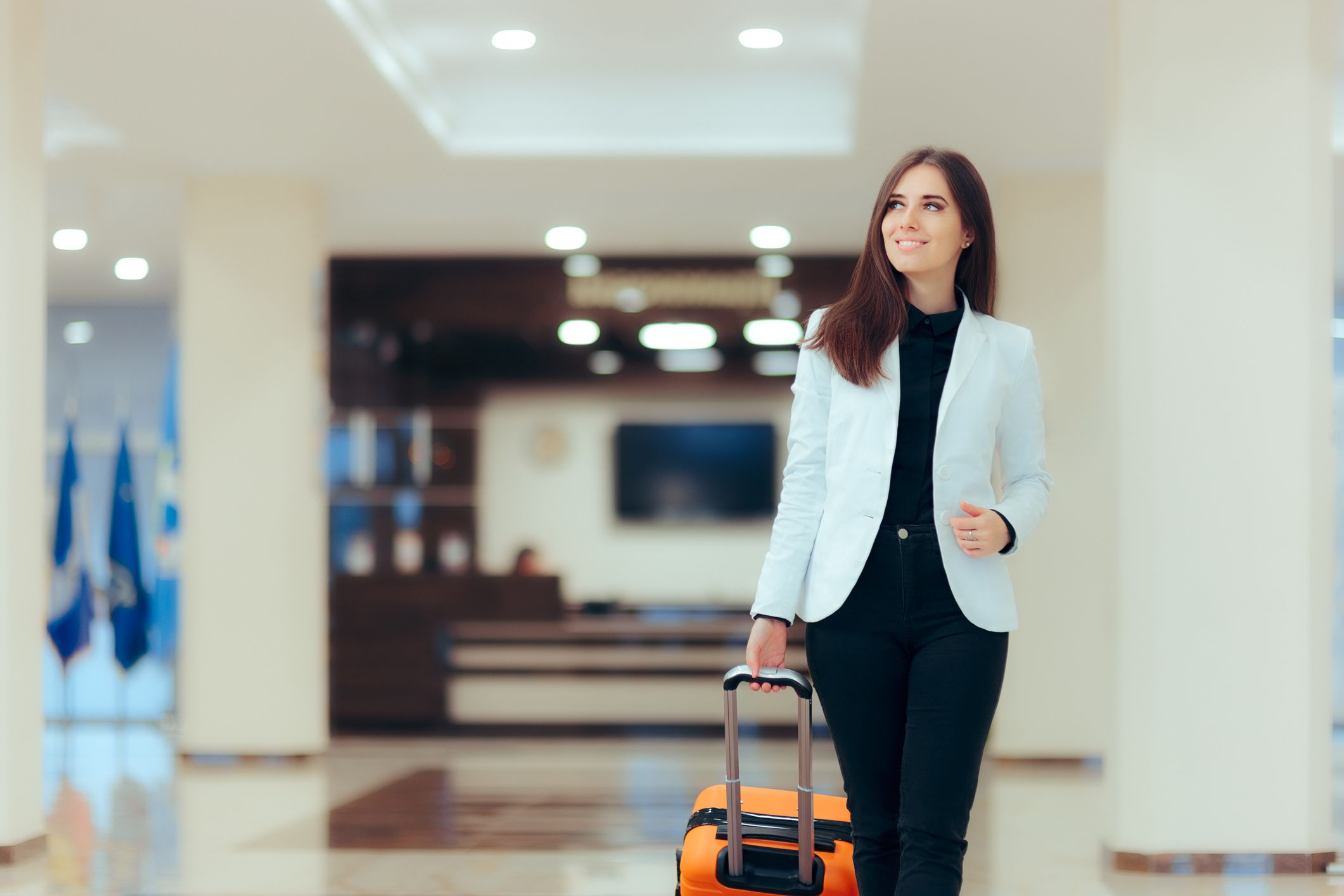 Female business woman pushing suitcase through airport 