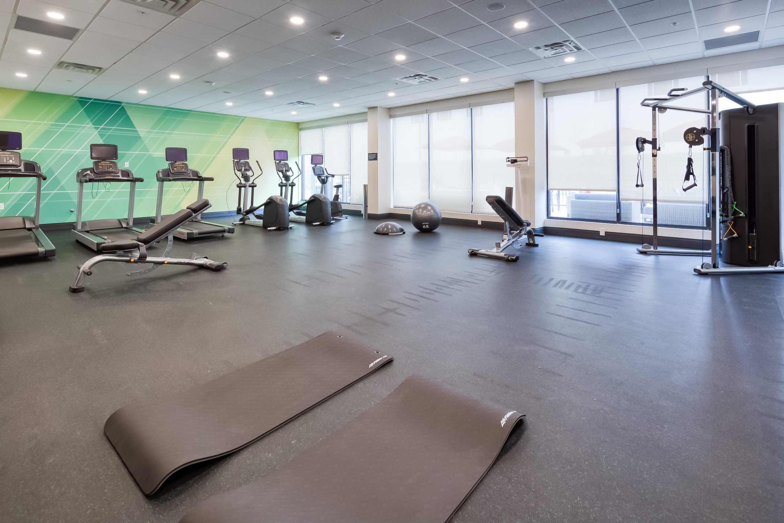 Modern hotel fitness center at Holiday Inn Nashville Airport with cardio machines, strength equipment, and yoga mats in a bright, spacious room.